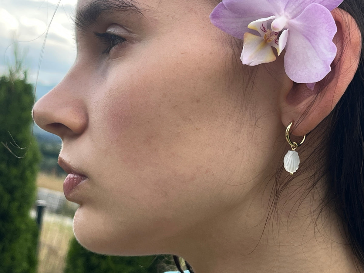 Mušľové náušnice Seashell pri nosení – bočný pohľad s orchideou