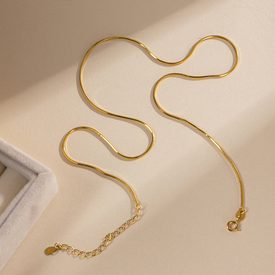 Pozlátená hadia retiazka Snake Elegance na béžovom pozadí